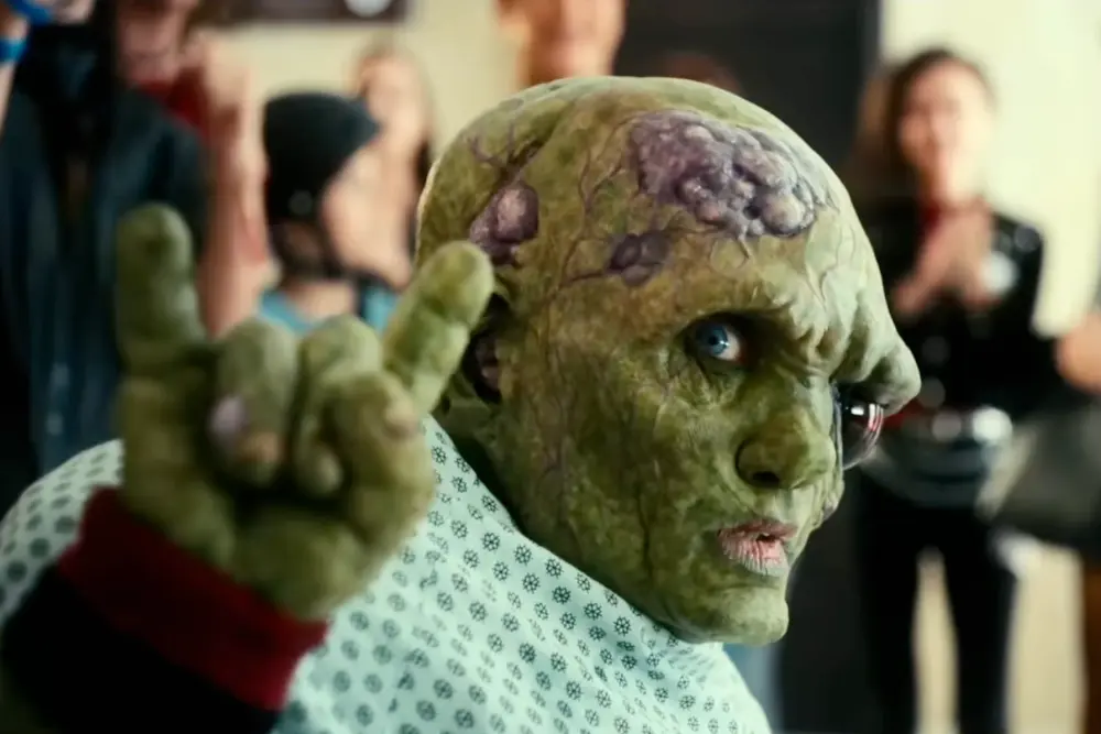 The Toxic Avenger character in the 2025 film, making a signature hand gesture, showcasing the movie’s monstrous and grotesque redesign